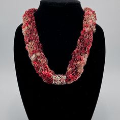 This beautiful necklace sparkles like gemstones.  Made with ladder yarn, it is super lightweight and easily slips on over the head (no clasp to come undone or tangle in your hair).  Because it is hand-knitted,  it has a nicely rounded rope-like appearance with a decorative scrollwork slide to add a touch of class.

This necklace is available in a wide range of colors.  If you don’t see the color you are looking for, contact us with specific requests.  Customized necklaces are available for a sma Handmade Bohemian Yarn Jewelry, Hand Knitted Jewelry As A Gift, Red Handwoven Necklace For Gift, Elegant Red Handwoven Jewelry, Handwoven Multi-strand Jewelry Gift, Red Handwoven Necklace, Handwoven Red Necklace, Red Adjustable Handwoven Necklace, Unique Red Handwoven Necklace