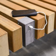 an electronic device plugged into the side of a wooden bench