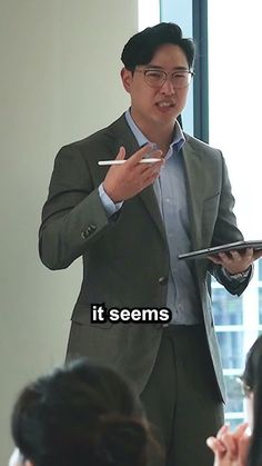 a man standing in front of a group of people while holding a pen and paper