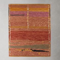 an orange, pink and yellow rug hanging on a wall