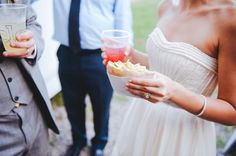 a woman in a white dress holding a drink and a cup with food on it