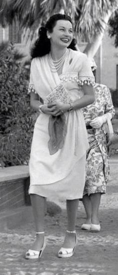 an old black and white photo of two women walking down the street with flowers in their hands