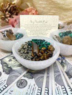 two bowls filled with rocks and money on top of a table next to a note