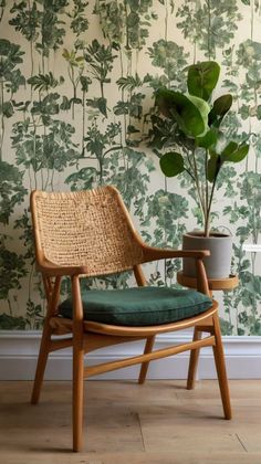 a chair sitting next to a potted plant in front of a wallpapered wall