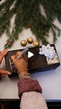 a person is decorating a box with chocolates on the table next to christmas tree