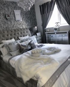 a bedroom with a bed, chandelier and pillows on it's headboard