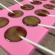 chocolate cake pops are lined up on a pink tray with white sticks sticking out of them