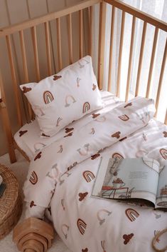 a bed with a book on top of it next to a basket and pillow case