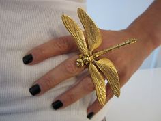 a woman's hand wearing a gold dragonfly ring