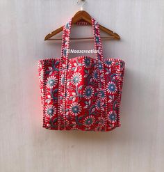 a red and blue bag hanging from a wooden hanger next to a white wall