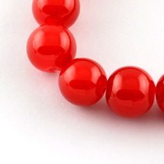 red beads are arranged in a row on a white surface with one bead facing the camera