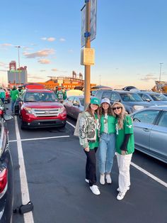 two girls standing in the parking lot next to some parked cars with st patrick's day decorations on them