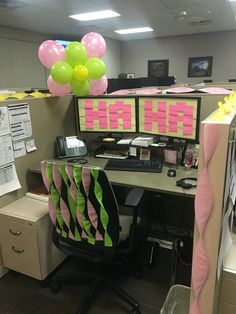 an office cubicle decorated with pink, green and yellow balloons