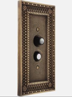 an old fashioned metal light switch cover with two black knobs on it's side