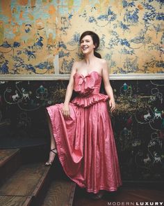 a woman in a pink dress sitting on some stairs