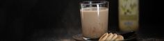 a chocolate milkshake and some cookies on a black plate with a bottle in the background