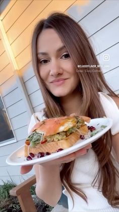 a woman holding a plate with a sandwich on it