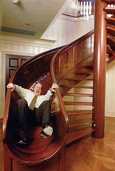 a man sitting on top of a wooden stair case in front of a spiral staircase