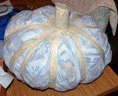 a white pumpkin wrapped in plastic sitting on top of a wooden table next to other items