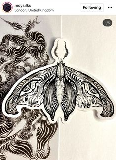 an intricately designed paper cut butterfly sitting on top of a piece of white paper