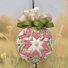 a pink and green ornament hanging from a pole with a bow on it