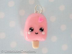 a pink ice cream with black eyes and a bow on it's head is hanging from a silver chain