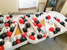 three boxes filled with black, white and red balloons sitting on top of a table