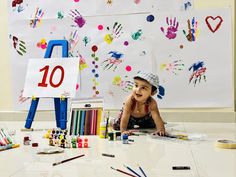 a young child laying on the floor in front of some art supplies and paper work