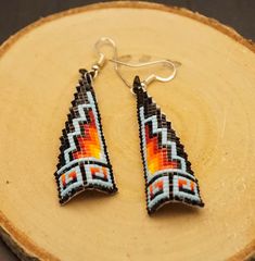 a pair of earrings sitting on top of a piece of wood next to a tree