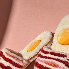 a pair of red and white striped slippers with an egg in the middle on a pink background