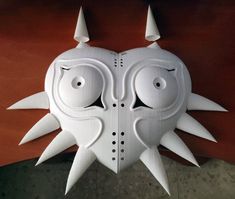 a white mask with spikes on it's head and eyes is hanging from the ceiling