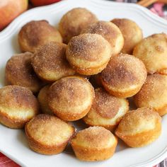 a white plate filled with sugared donuts on top of a red and white checkered table cloth