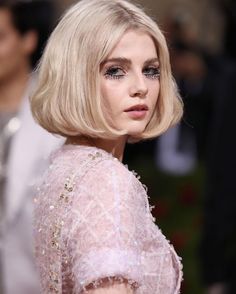 a woman with blonde hair wearing a pink dress and black eyeliners on the red carpet