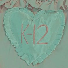 a heart shaped pillow with the number k2 on it's side and ruffled edges