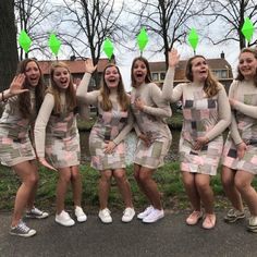 a group of young women standing next to each other on top of a road in front of trees