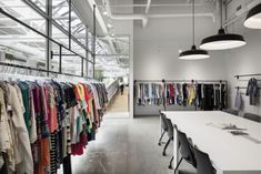 a room filled with lots of clothes hanging from the ceiling and tables in front of it