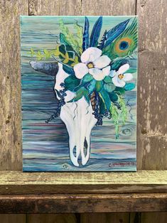 a painting of a cow skull with white flowers and peacock feathers on it's head