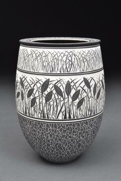 a black and white vase with designs on it's sides, sitting on a gray surface