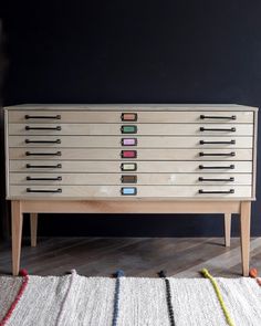 a chest of drawers sitting on top of a wooden floor next to a white rug