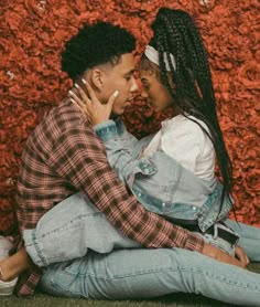 a man and woman sitting on the ground next to each other with their arms around each other