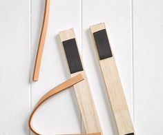 two pieces of wood are laying next to each other on a white surface, one is holding a black object and the other has a wooden handle