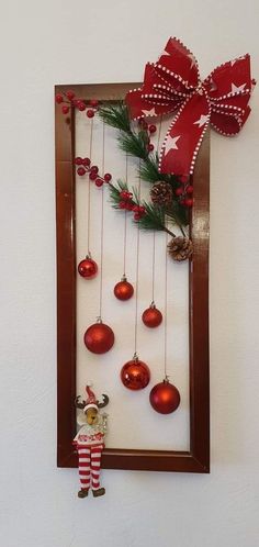 a wooden frame with ornaments hanging from it's sides and a red bow on top