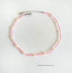 a pink and yellow beaded bracelet on a white surface with a silver chain attached to it