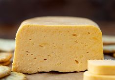 a piece of cheese sitting on top of a table next to crackers