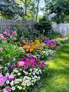 colorful flower garden in front of a white picket fence