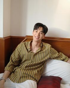 a man sitting on top of a bed next to pillows