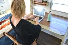 a woman sitting at a table using a laptop computer