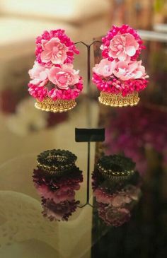 pink flowers are hanging from the top of a glass display stand with two rings on it