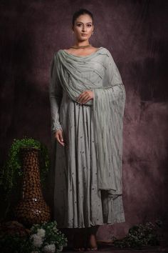 Ash grey deep round neckline flared anarkali with sequin embellishments and attached dupatta. Comes with matching pant.
Components: 3
Pattern: Embroidery
Type Of Work: Sequin, Beads, Pipe Work
Neckline: Round Neck
Sleeve Type: Full Churidar Sleeves
Fabric: Viscoes Silk, Soft Net, Lining: Cotton
Color: Grey
Other Details: 

Attached inner lining
Attached dupatta
Length:
Anarkali(in inches): 55         
  Pant(in inches): 39


Occasion: Mehendi and Haldi - Aza Fashions Churidar Sleeves, Silk Anarkali, Embroidered Anarkali, Long Kurti Designs, Gray Silk, Net Dupatta, Indian Fashion Designers, Silk Embroidery, Pants Design