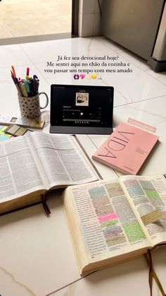 an open book sitting on top of a table next to a cup and laptop computer